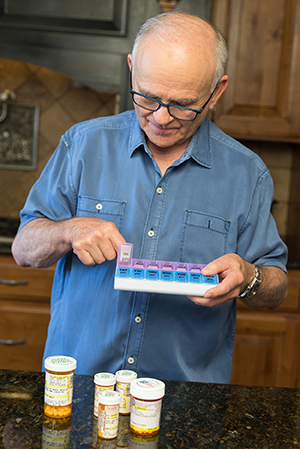 Un hombre toma pastillas en la cocina.