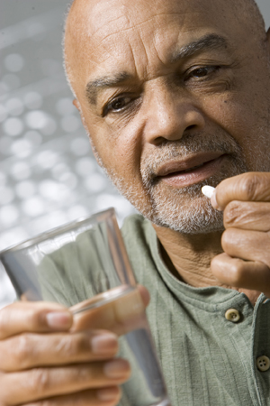 Hombre que sostiene un vaso de agua, preparándose para tomar una pastilla.