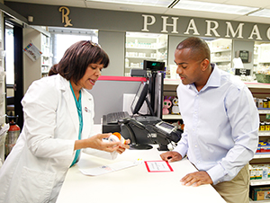 Farmacéutica hablando con un hombre en el mostrador de la farmacia.