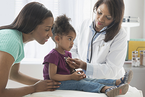 Proveedor de atención médica escuchando los sonidos del pecho de una niña con un estetoscopio.