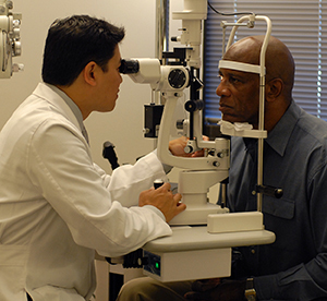 Proveedor de atención médica examinando los ojos de un hombre.