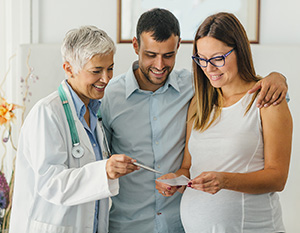 Médico hablando con una pareja que espera un bebé.